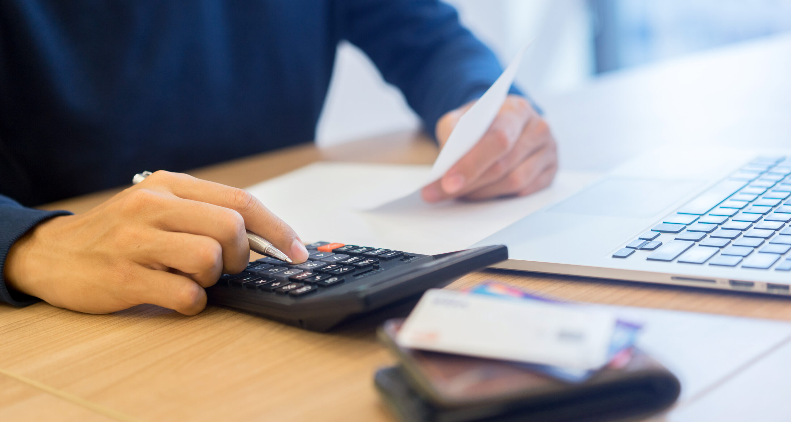 close up man hand press on calculator and holding financial bill