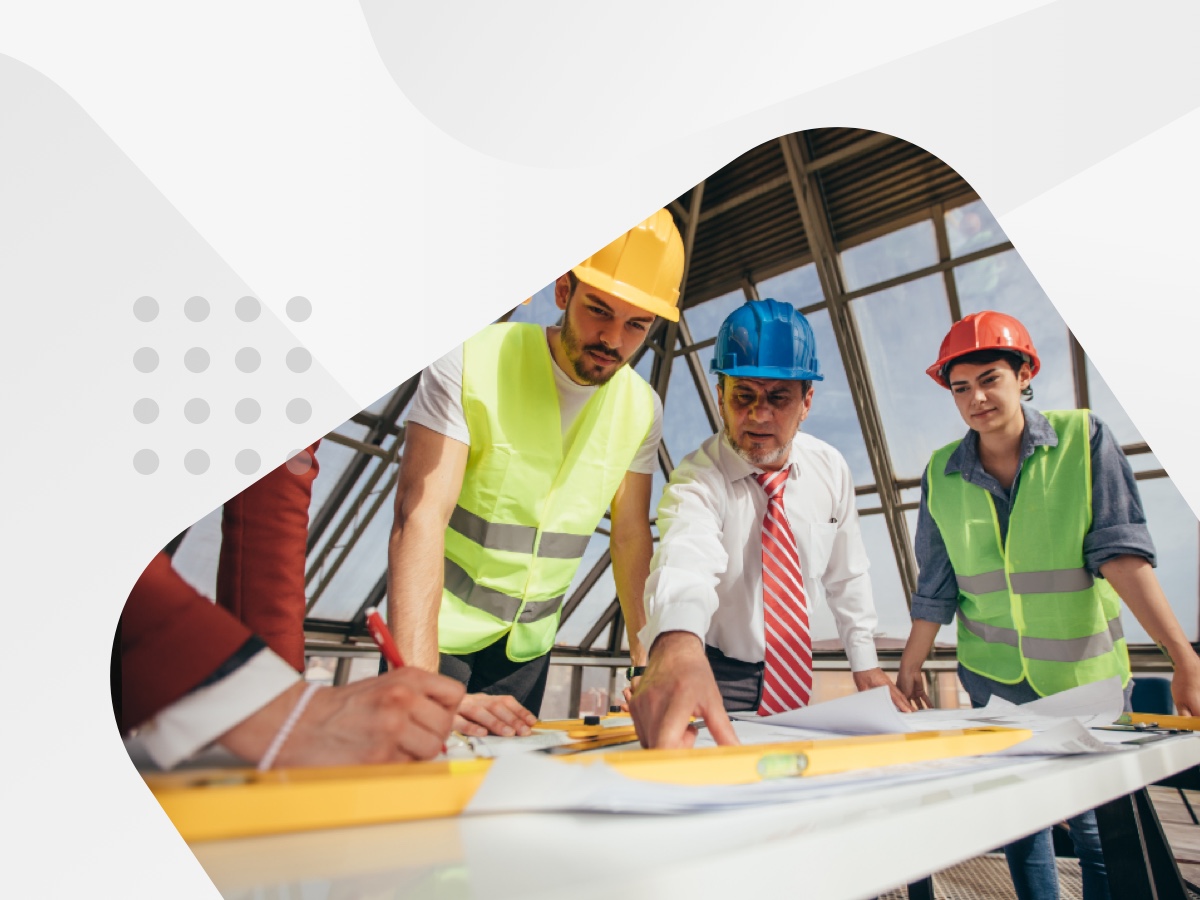 A team of workers in hard hats and vests collaborating on construction plans.