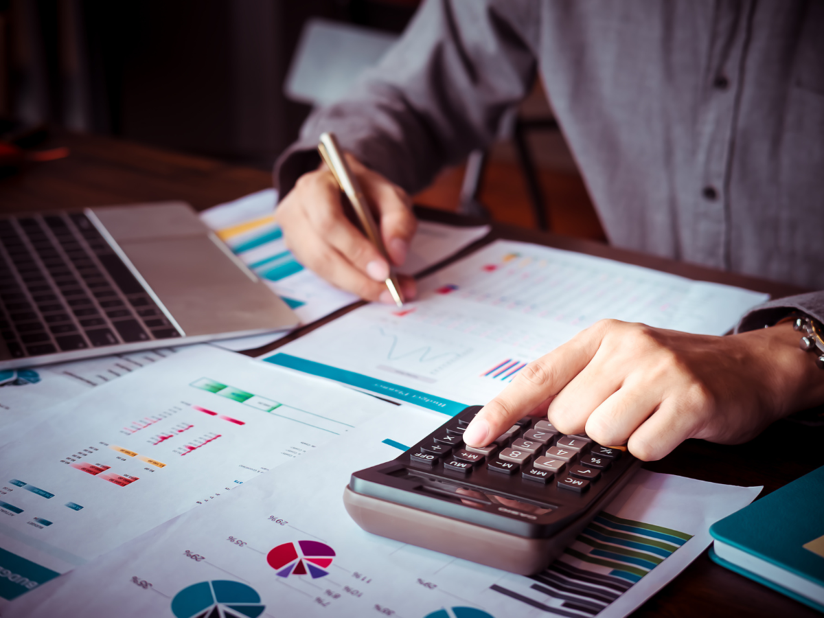 A businessman using a calculator and laptop to calculate financial data.